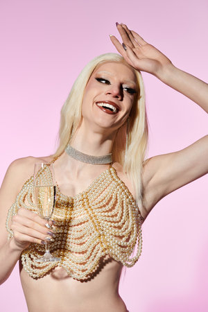Stylish drag queen holds a glass, beaming with joy against a pastel background at an event.のeditorial素材