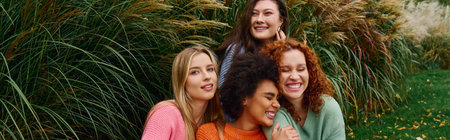 Four stylish friends laugh and share confidence in a vibrant outdoor park.