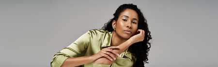 Elegant African American woman in stylish outfit poses gracefully with stunning jewelry.の写真素材