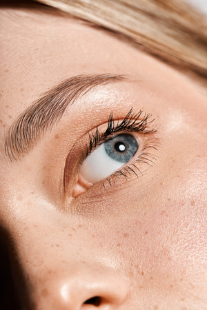 A young beautiful woman showcases her captivating eye and flawless skin under soft natural light.の写真素材