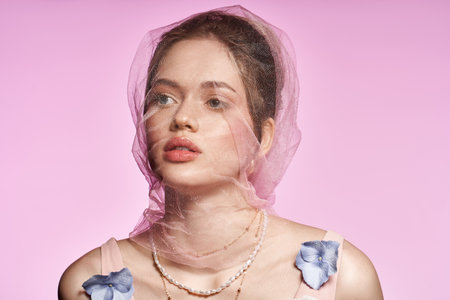 Young woman displays chic spring attire with floral accents and soft layers in a vibrant setting.の写真素材