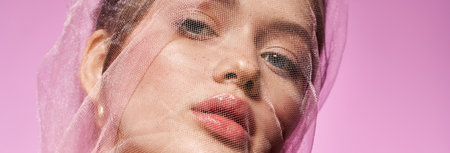 Charming young woman with delicate features wearing sheer fabric, embodying elegance and trendiness.の写真素材