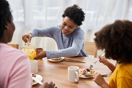 Family enjoys a warm breakfast together, sharing laughter and bonding over delicious food.の写真素材