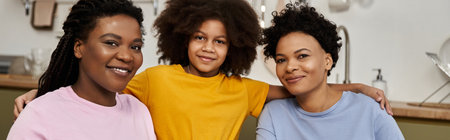 Two loving parents smile with their daughter, celebrating togetherness in a cozy space.の写真素材
