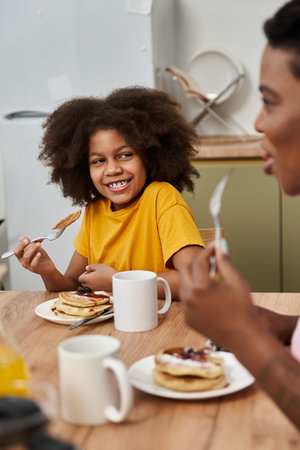 A vibrant family moment over breakfast fosters joy and connection at their cozy kitchen table.の写真素材