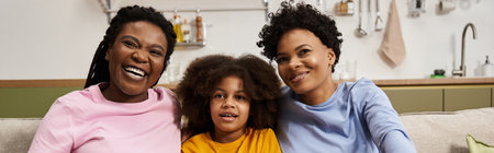 Three family members share joyful moments, filled with laughter and love while seated on the couch.の写真素材