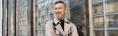 Stylish senior man confidently walking through an urban cityscape in chic attire during a sunny afternoonの写真素材