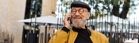 Stylish senior man confidently chatting on his phone while enjoying the vibrant city atmosphereの写真素材
