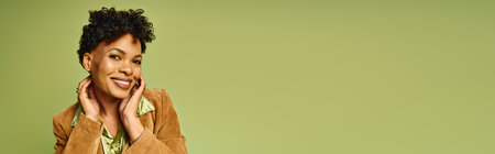 A lovely african american woman showcases her trendy outfit while posing with a warm smile indoors.の写真素材