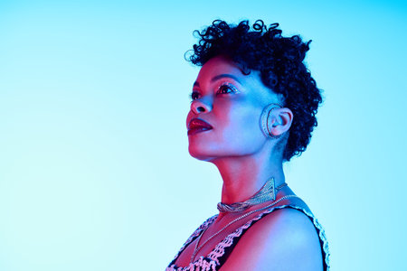 Stylish African American woman poses confidently under dynamic blue and pink lights, exuding charm.の写真素材