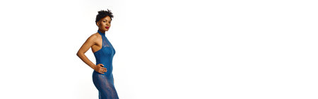 A stylish African American woman confidently poses in a striking blue dress.の写真素材
