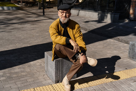 Stylish senior man enjoys a leisurely stroll through the urban landscape while sporting a chic and fashionable outfitの写真素材