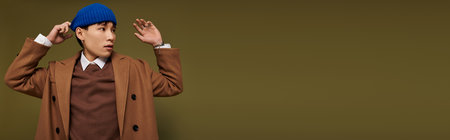 A young handsome man in a stylish outfit exudes confidence and creativity while striking a pose.の写真素材