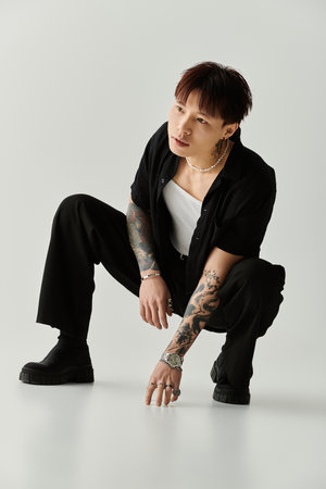 A stylish young Asian man crouches in a contemporary studio, exuding creativity and confidence.の写真素材