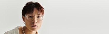 A young, fashionable Asian man stands in a clean and modern setting, showcasing his unique style.の写真素材