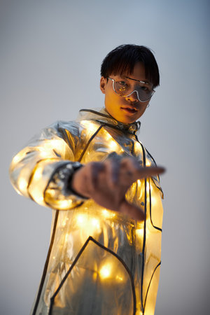 Young man showcases his fashion forward style with glowing details in a trendy indoor space.の写真素材