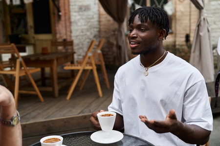 Two handsome men share laughter and connection over coffee in an inviting cafe setting.の写真素材