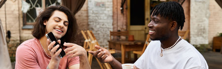 A charming gay couple laughs and enjoys drinks at a cafe on a sunny day.の写真素材