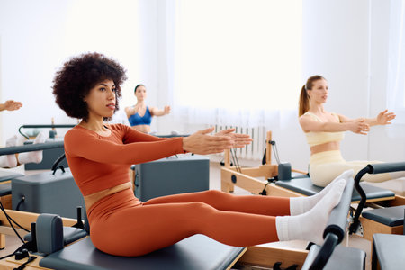 Participants perform pilates exercises focusing on core strength and flexibility in a bright space.の写真素材
