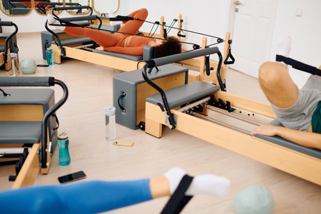 A group takes a tough pilates class with reformer machines for strength training.の写真素材
