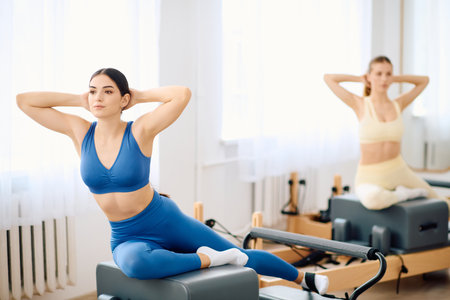 Two dedicated individuals engage in a pilates workout in a bright and spacious studio.の写真素材