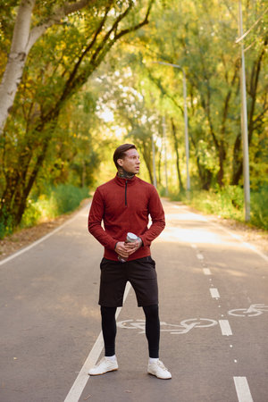 A young man in athletic wear poses confidently on a tree lined path, showing off his style.のeditorial素材