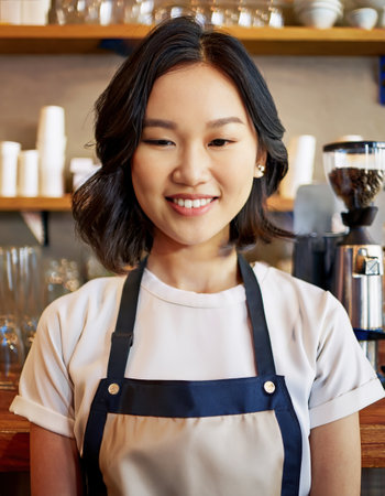asian girl, barista with a warm smile prepares coffee for students in a vibrant college cafe setting.の素材