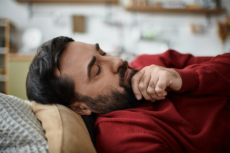 An elderly man in casual attire enjoys a moment of peace while resting indoors.のeditorial素材