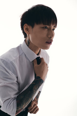 A young handsome Asian man adjusts his tie with a thoughtful expression, radiating charm and style.のeditorial素材