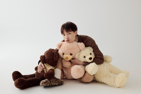 A young handsome asian man cuddles plush teddy bears, creating a whimsical and cozy atmosphere.の写真素材