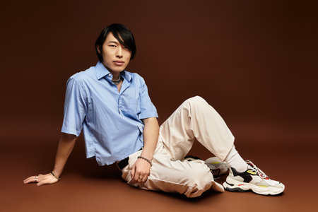A fashionable asian man relaxes in a contemporary studio, showcasing his unique style.の写真素材