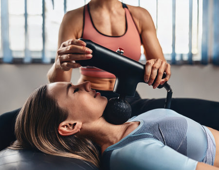 One woman using massager on another woman during relaxing session.の素材