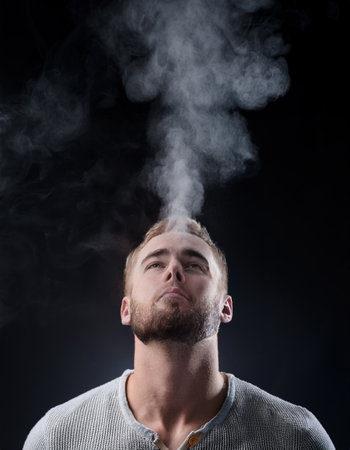 A man enjoys a moment of reflection, releasing steam of smoke as he practices relaxation techniques.の素材
