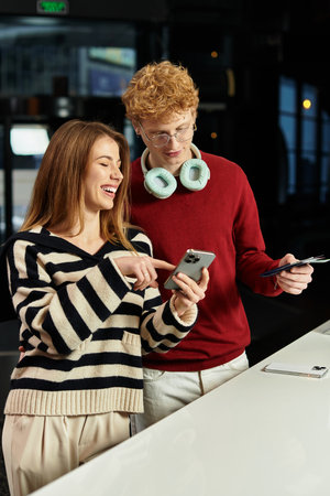 A couple is enjoying their time in a hotel, sharing smiles and laughter over a smartphone.の写真素材