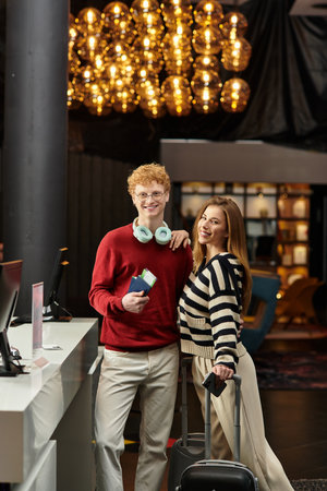 A young couple is checking into a trendy hotel, beaming with happiness and love for each other.の写真素材