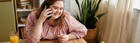 A young woman with Down syndrome relaxes at home, smiling and talking on the phone with excitement.の写真素材