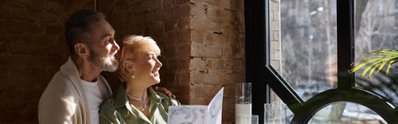 Middle aged couple smiles while looking at the menu, enjoying a sweet moment together, bannerの写真素材