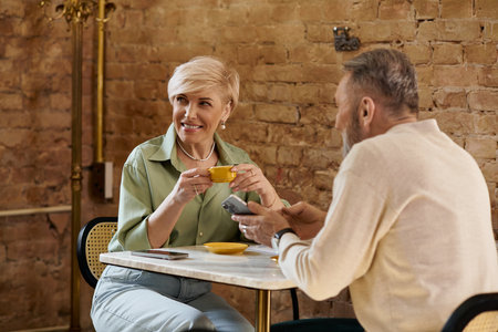 A middle aged couple shares smiles over coffee at a charming cafe, sharing a special moment.の写真素材