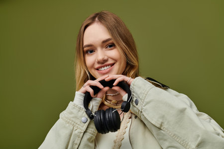 Bright colors enhance a young womans stylish outfit as she playfully holds headphones.の写真素材