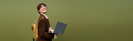 A young woman in stylish clothes smiles as she types on her laptop.
