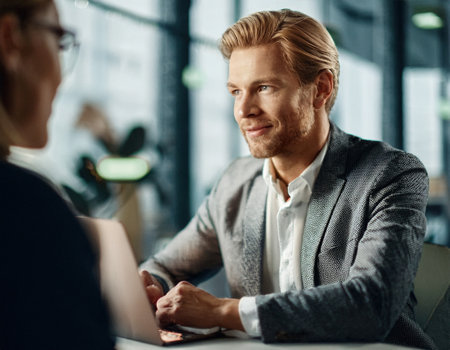 Two professionals engage in a productive conversation at a sleek office table while exploring ideas.の素材