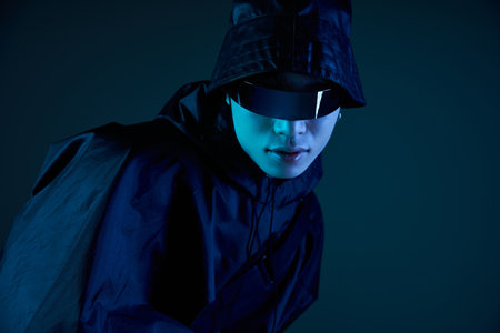 Asian man shows off his style in shades and a sleek outfit under dim light.の写真素材