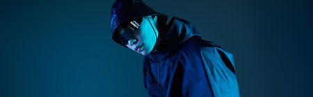 A young handsome man poses confidently in a stylish outfit, illuminated by blue light in a studio.の写真素材