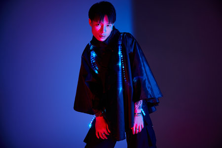 Fashionable young man showcases modern style with illuminated details and bold colors at night.の写真素材