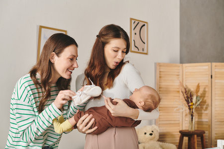 Two loving mothers share a sweet moment with their baby, enjoying Mothers Day in a cozy home.の写真素材