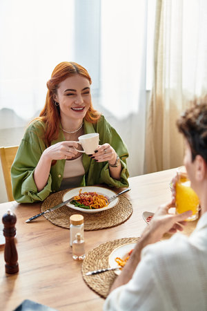 Two young lovers enjoy a delightful meal together, smiling and savoring their time at home.の写真素材