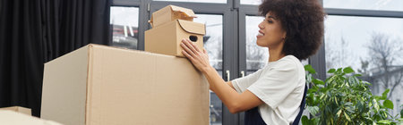 A woman stacks cardboard boxes in a modern room, ready for relocation.
