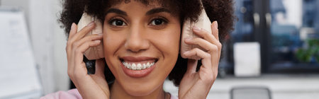A young woman packs boxes in her stylish apartment, enjoying upbeat music through headphones.