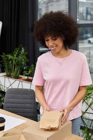 A young woman packs items in a green filled office, getting ready for her move.