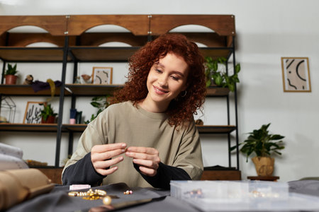 A young woman creates unique jewelry, highlighting her artistic talent and design skills.の写真素材
